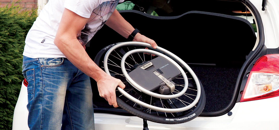 De aandrijfwielen van de WheelDrive in de kofferpak van een auto tillen.